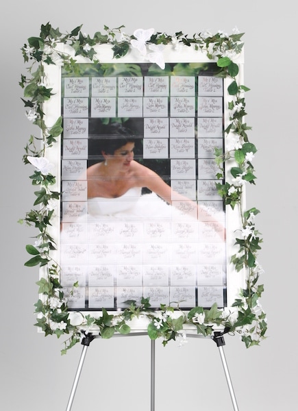 celebration seating board with bride in dress partially revealed by some name tags on celebration board